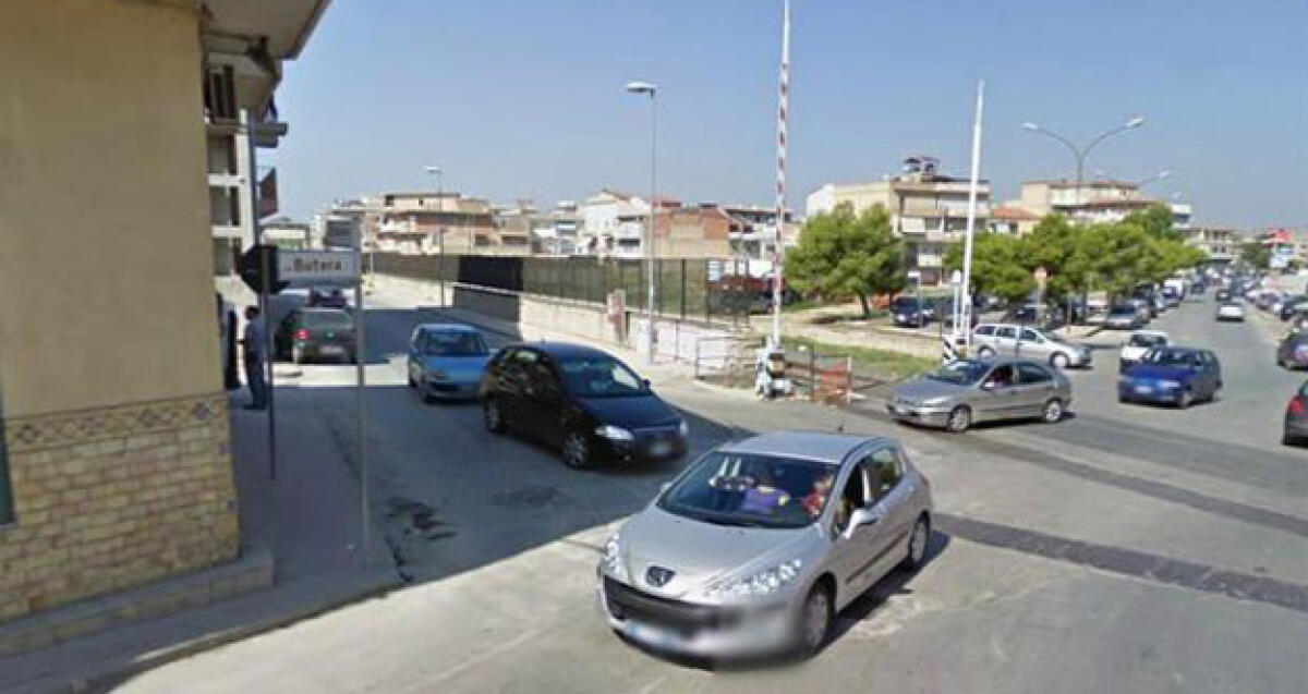 Via Butera, le barre del passaggio a livello restano alzate mentre transita il treno -